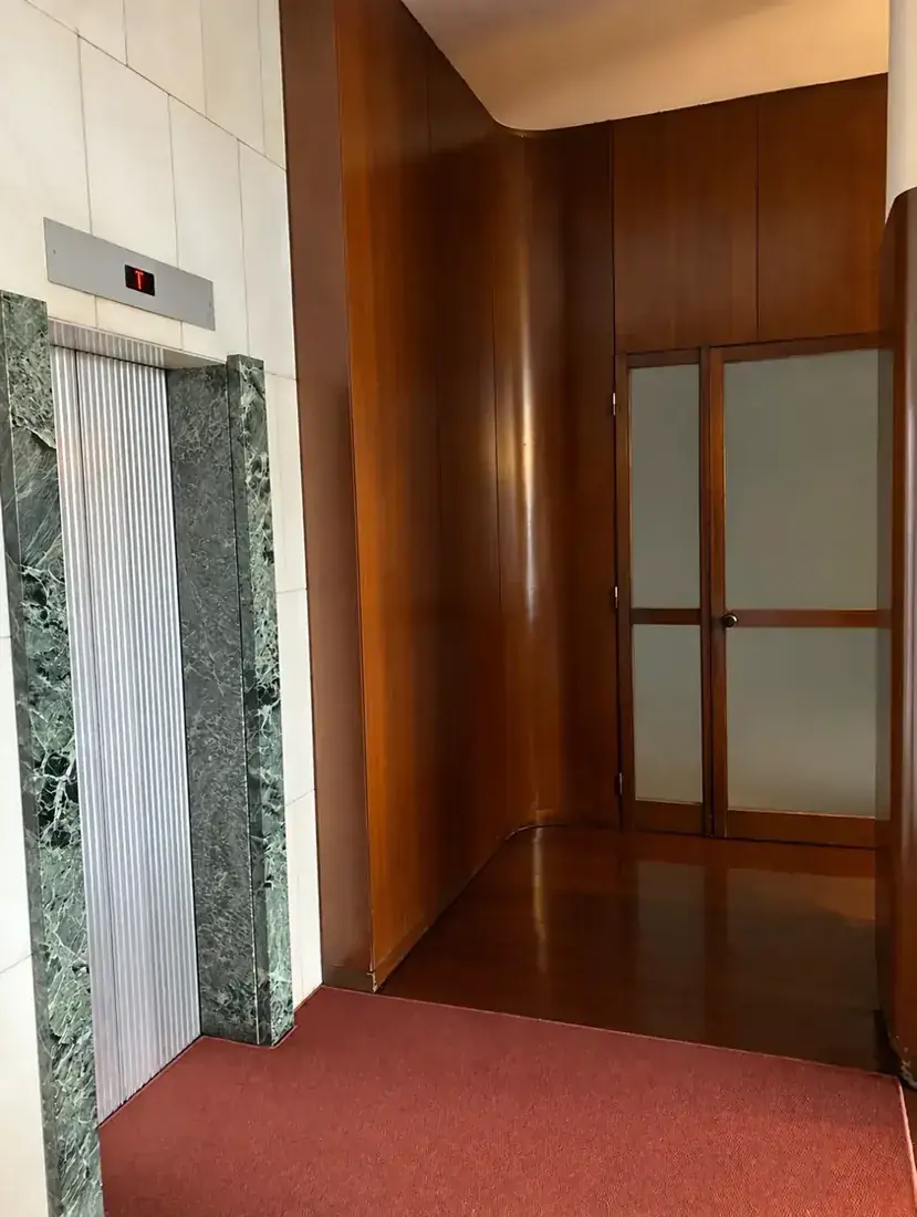 Ușa de sticlăDeschideți ușa de sticlă de lângă lifturi și mergeți la containerele din spatele recepției portarului.